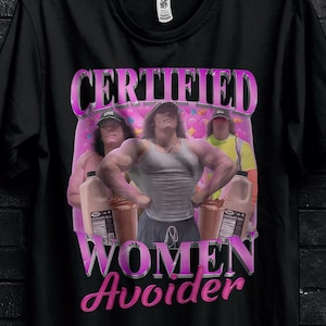 Peut inclure: T-shirt noir avec un motif graphique rose « CERTIFIED WOMEN Avoider » et une image de trois hommes. Le t-shirt porte également le logo Stitch Aura et une promotion « BULK50 ».