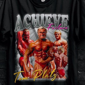 May include: Black t-shirt featuring a graphic of bodybuilders with the text "ACHIEVE Failure" and "Tom Platz". The shirt also has the Stitch Aura logo and a promotional offer.