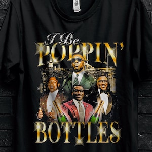 Può includere: T-shirt nero con una grafica di un gruppo di uomini e la scritta "I Be POPPIN' BOTTLES". La maglietta ha anche la scritta "BULK50" e "SHOP NOW".