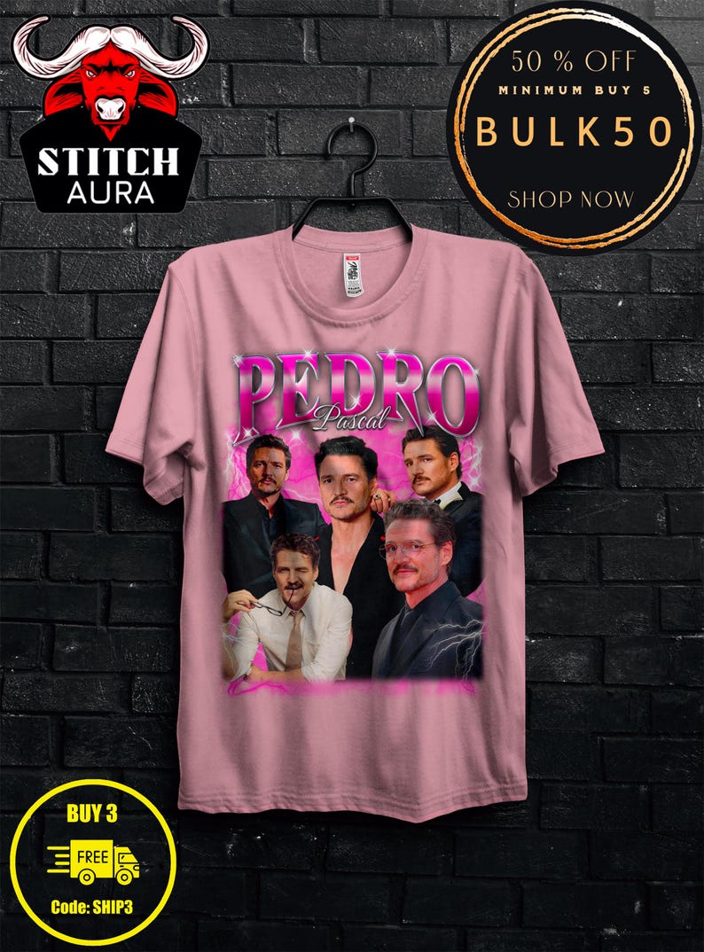 May include: A light pink t-shirt featuring a graphic of Pedro Pascal in various poses. The word "PEDRO" is in large, stylized letters above "Pascal". The shirt has a crew neck and short sleeves. The Stitch Aura logo is in the upper left corner.