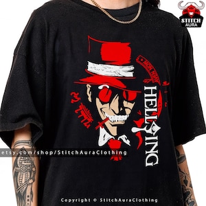 May include: Black t-shirt featuring a red and white graphic of a character with a top hat, sunglasses, and a cigarette. The word "HELLSING" is printed vertically in white. The shirt also has the text "AVEN NOW" and other Japanese text.