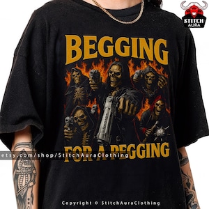 Puede incluir: Camiseta negra con un diseño gráfico que presenta figuras esqueléticas sosteniendo armas contra un fondo de llamas. El texto "BEGGING FOR A BEGGING" está impreso en amarillo.