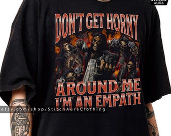 Könnte beinhalten: Schwarzes T-Shirt mit einer Grafik von Skelettfiguren mit Waffen, Flammen und dem Text "DON'T GET HORNY AROUND ME I'M AN EMPATH." Das Shirt enthält den Etsy-Shop-Namen und Copyright-Informationen.
