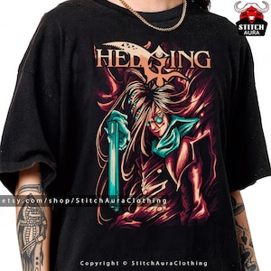 May include: Black t-shirt featuring a graphic design with the word "HELLSING" in orange, and an illustration of a character with long hair, glasses, and a teal weapon. The design has red and teal accents.