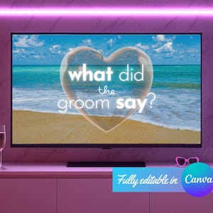 May include: A flat-screen TV displays a beach scene with the text "what did the groom say?" inside a heart-shaped bubble. The TV sits on a pink cabinet, with champagne flutes and balloons nearby. Pink lighting accents the room.