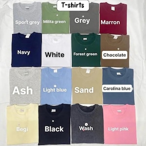 May include: A collection of sixteen crew neck t-shirts arranged in a grid, featuring various solid colors including sport grey, military green, grey, maroon, navy, white, forest green, chocolate, ash, light blue, sand, carolina blue, begi, black, wash, and light pink.