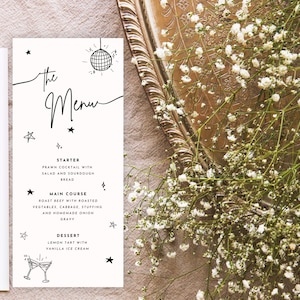 Może przedstawiać: Biała karta menu z czarnym tekstem i ilustracjami gwiazd i kuli dyskotekowej. Menu zawiera przystawkę, danie główne i deser. Menu znajduje się obok dekoracyjnej złotej tacy i białych kwiatów.