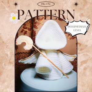 May include: A crocheted angel doll with a white body, wings, and halo, holding a wooden wand. The image includes the text "DIGITAL PATTERN" and "INTERMEDIATE LEVEL". The angel is sitting on a light blue surface.