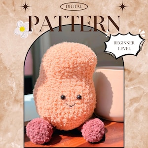 May include: A soft, peach-coloured stuffed toy with a smiling face and two small, round, pink feet. The image includes the text "DIGITAL PATTERN" and "BEGINNER LEVEL". The toy is designed to be a beginner-level project.