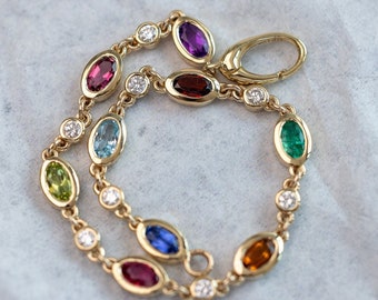 May include: A gold chain bracelet with oval-shaped gemstones in various colors, including purple, red, green, blue, and yellow. The bracelet also features small round diamonds.