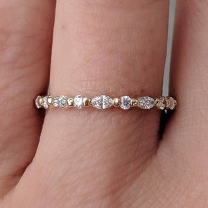 May include: A delicate gold band ring with a row of small, oval-shaped diamonds set in a pave setting.
