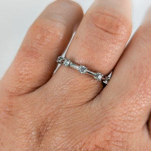 May include: A silver band ring with small round diamonds set in a delicate design.