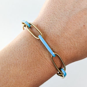 Peut inclure: Un bracelet en cha&icirc;ne dor&eacute;e avec des accents en &eacute;mail bleu clair. Le bracelet est compos&eacute; de maillons ovales.