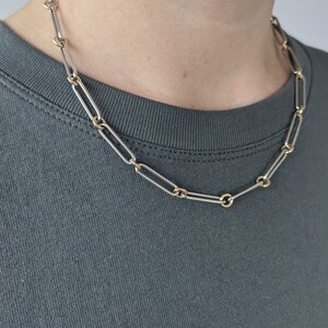 May include: A silver and gold chain necklace with a link design. The chain is made of two different metals, with the links alternating between silver and gold.