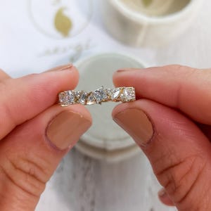 May include: A gold band ring with a row of irregularly shaped diamonds set in a pave setting.