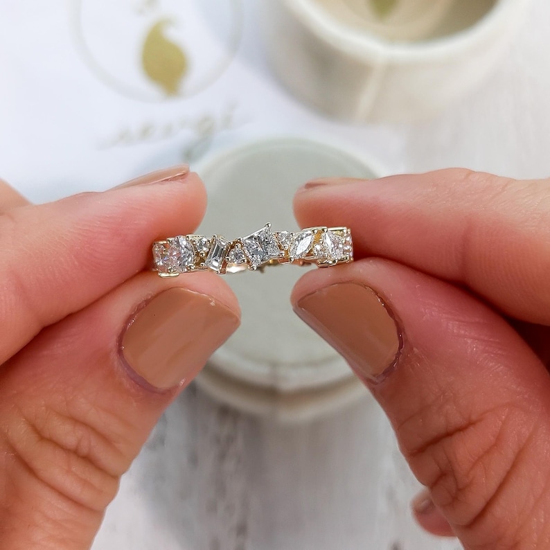 May include: A gold band ring with a row of irregularly shaped diamonds set in a pave setting.
