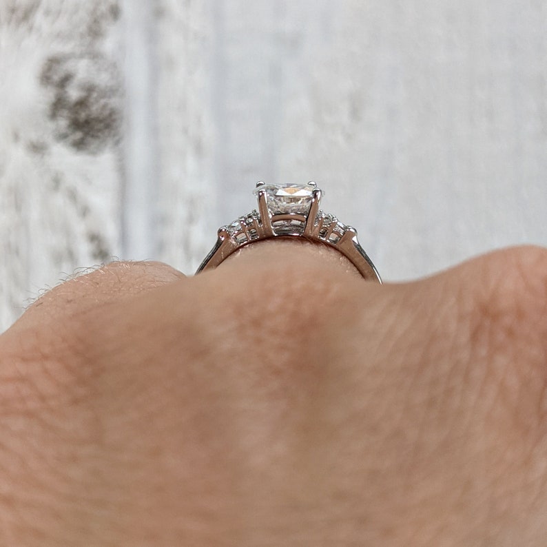 May include: A silver engagement ring with a large, clear, square-shaped center stone and smaller accent stones on the band.