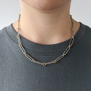 May include: A silver and gold chain necklace with a simple, linked design. The chain is made of two different metals, with the links alternating between silver and gold.