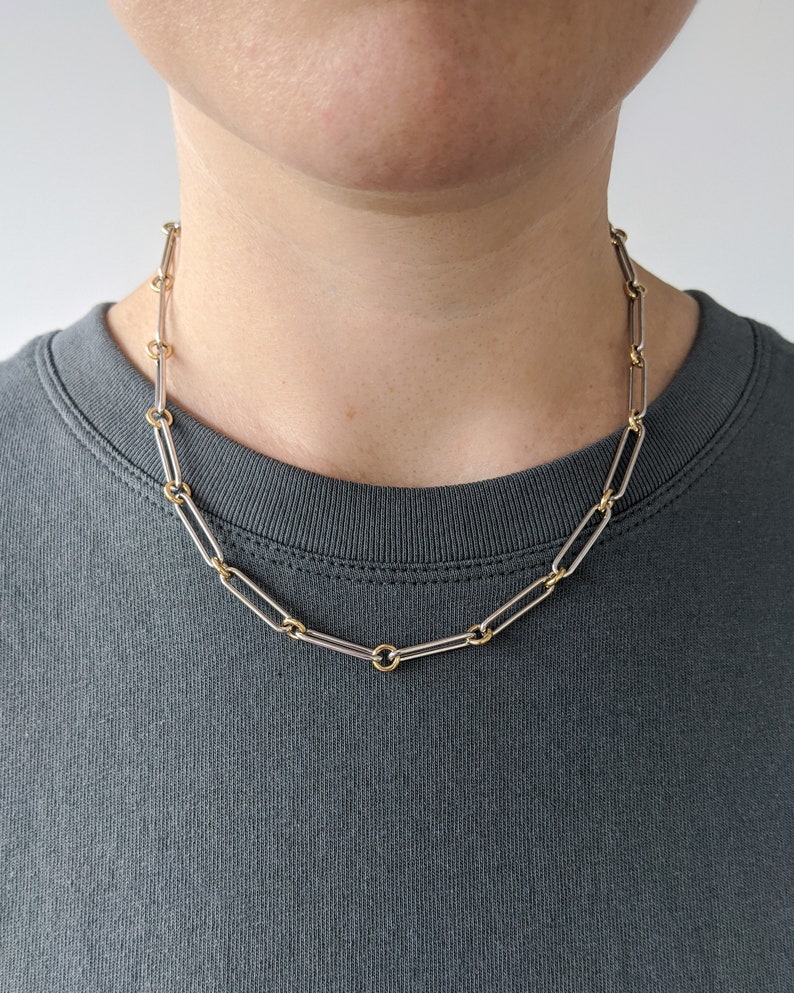May include: A silver and gold chain necklace with a simple, linked design. The chain is made of two different metals, with the links alternating between silver and gold.