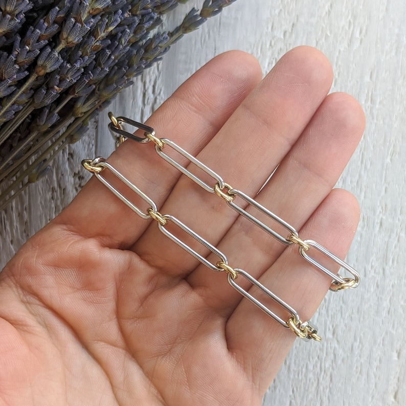 May include: A silver and gold chain necklace with a link style. The chain is made of two different metals, one silver and one gold.