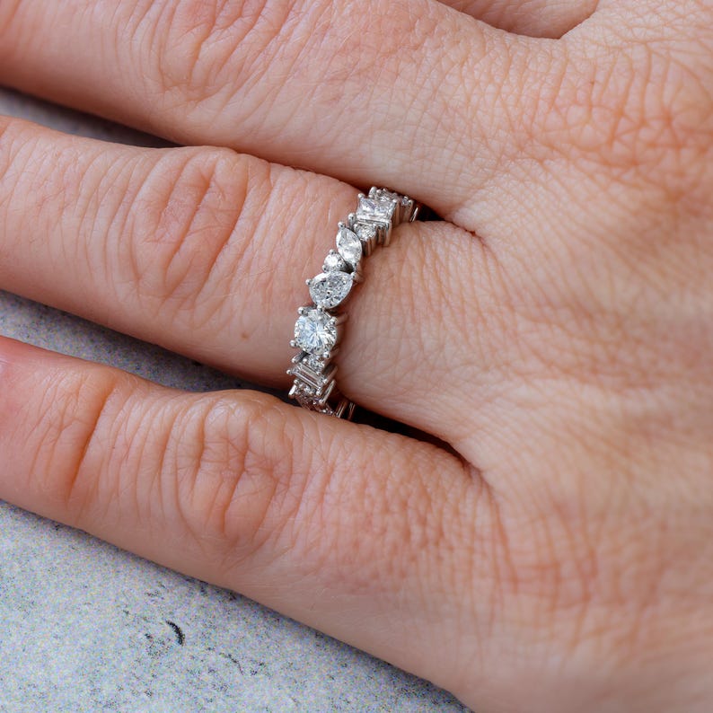 May include: A silver band ring with a row of pear-shaped and round diamonds.