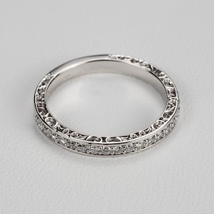 May include: A delicate silver band with a filigree design and a row of small diamonds.