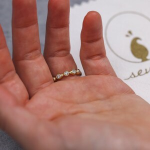 May include: A gold band ring with five small round diamonds set in a curved line.