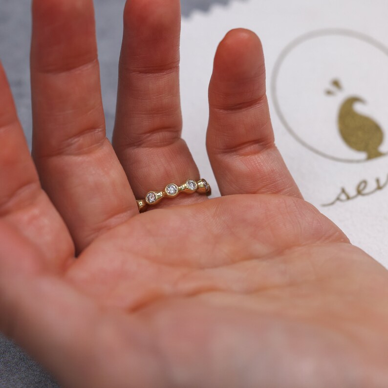 May include: A gold band ring with five small round diamonds set in a curved line.