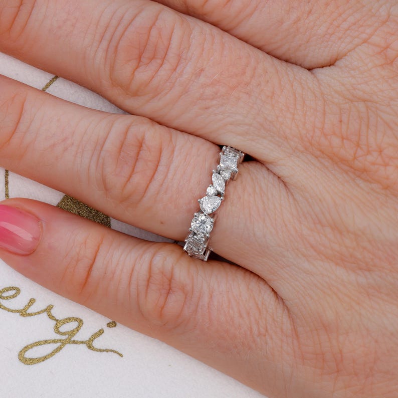 May include: A silver band ring with a row of pear-shaped and round diamonds.