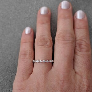 May include: A delicate silver band with a row of small, clear marquise-shaped stones.
