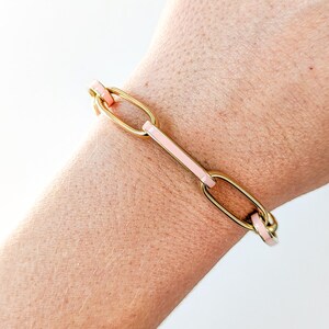 Peut inclure: Un bracelet en cha&icirc;ne dor&eacute;e avec des accents en &eacute;mail rose. Le bracelet est compos&eacute; de maillons ovales.