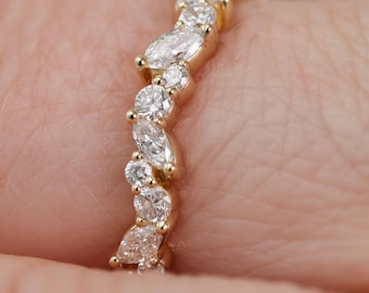 Puede incluir: Un anillo de oro con una banda curva y ondulada engastada con una serie de diamantes blancos alternados en talla marquesa y talla brillante redonda. Las piedras están dispuestas en un patrón fluido y escalonado sobre la banda de oro amarillo pulido.