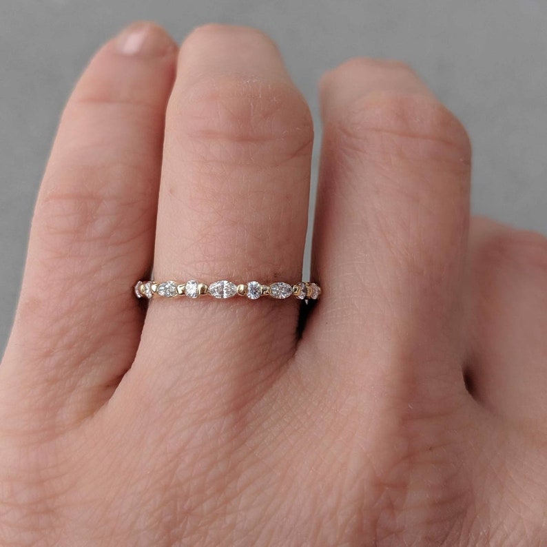 May include: A delicate gold band ring with a row of small, oval-shaped diamonds set in a pave setting.