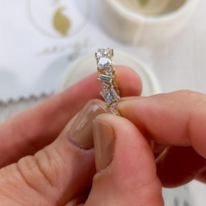 May include: A gold band ring with a row of various sized and shaped clear diamonds.