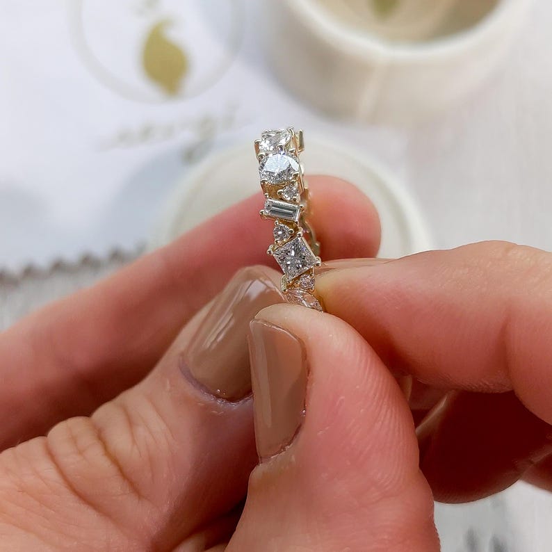 May include: A gold band ring with a row of various sized and shaped clear diamonds.