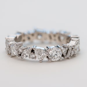May include: A silver band ring featuring a row of sparkling diamonds in various shapes and sizes.