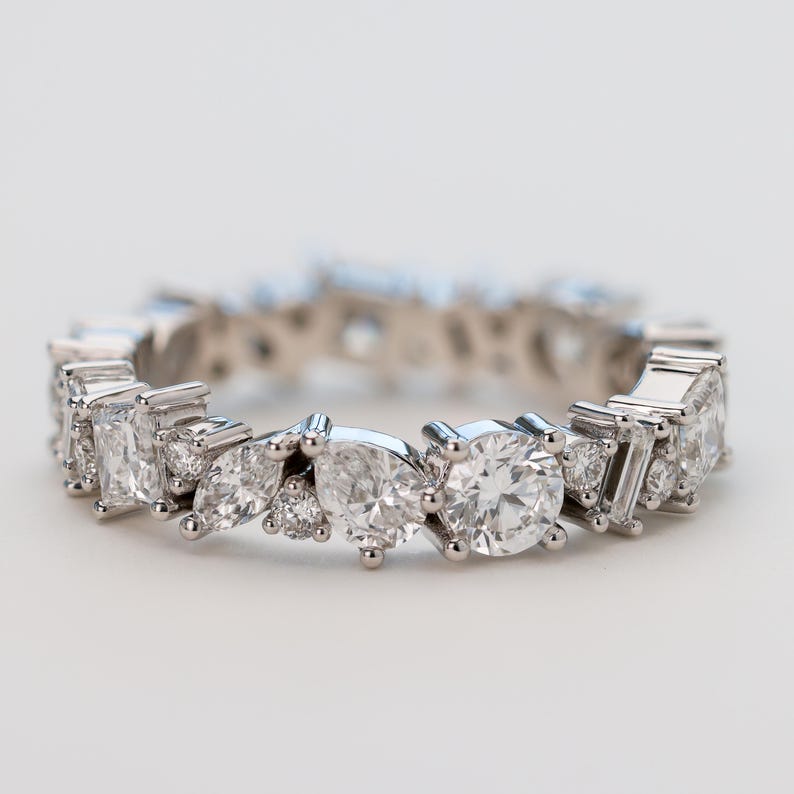 May include: A silver band ring featuring a row of sparkling diamonds in various shapes and sizes.