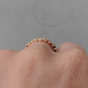 May include: A gold band ring with a row of small, clear diamonds set in a pave setting.