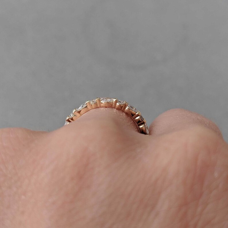 May include: A gold band ring with a row of small, clear diamonds set in a pave setting.
