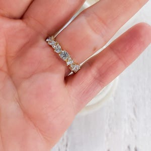 May include: A gold band ring with a row of clear, round, and baguette-shaped diamonds.