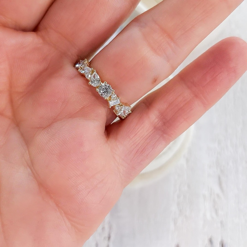 May include: A gold band ring with a row of clear, round, and baguette-shaped diamonds.
