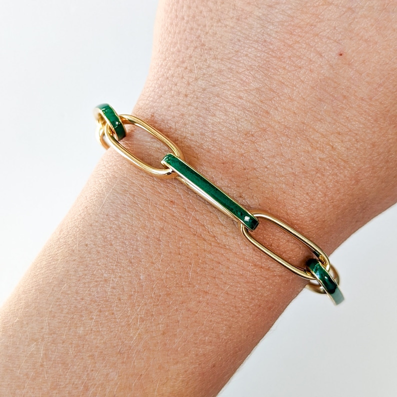 Peut inclure: Un bracelet en cha&icirc;ne dor&eacute;e avec des accents d'&eacute;mail vert. Le bracelet est compos&eacute; de maillons ovales et rectangulaires.