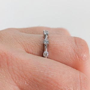 May include: A silver band with five small round diamonds set in a row.