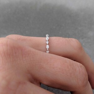 May include: A delicate silver band with a row of small, round diamonds.