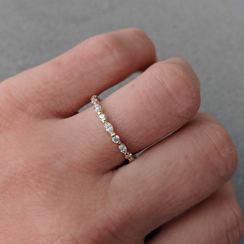 May include: A delicate gold band ring with a row of small, round diamonds set in a pave setting.