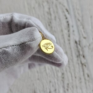 May include: A gold pendant with a detailed engraving of the Eye of Horus, a symbol of protection and good health in ancient Egyptian culture.