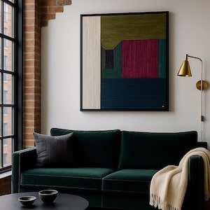 Könnte beinhalten: Ein modernes Wohnzimmer mit einem dunkelgrünen Samtsofa, einem schwarzen Couchtisch und einem gerahmten abstrakten Kunstwerk. Das Kunstwerk zeigt geometrische Formen in verschiedenen Farben. Eine goldene Wandleuchte und ein Fenster vervollständigen die Szene.