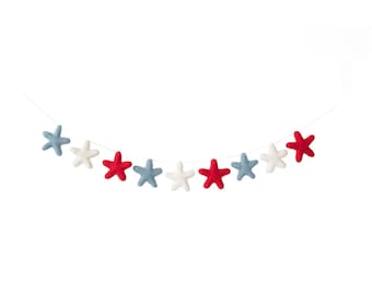 May include: A garland of felt stars in red, white, and blue. The stars are strung on a white string and are arranged in a curved pattern.