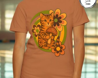 May include: A rust-colored t-shirt featuring a cartoon cat holding a mushroom. The cat is orange with black stripes, surrounded by retro-style flowers in orange, brown, and yellow. A green and yellow swirl is behind the cat.