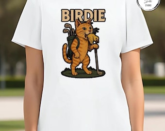 May include: White t-shirt featuring a cartoon orange tabby cat with golf clubs and a bird in its mouth. The word "BIRDIE" is printed above the cat in a brown, blocky font. The cat is standing on a patch of green grass.